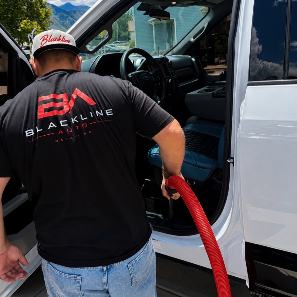 Blackline Auto technician detailing a truck interior in a driveway